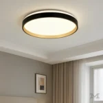 Luminaria Diane Black and Gold instalada en habitación moderna. Proporciona una iluminación suave y cálida, destacando el contraste entre el negro mate y el aro dorado. Perfecta para dormitorios o ambientes que buscan un toque de sofisticación contemporánea.