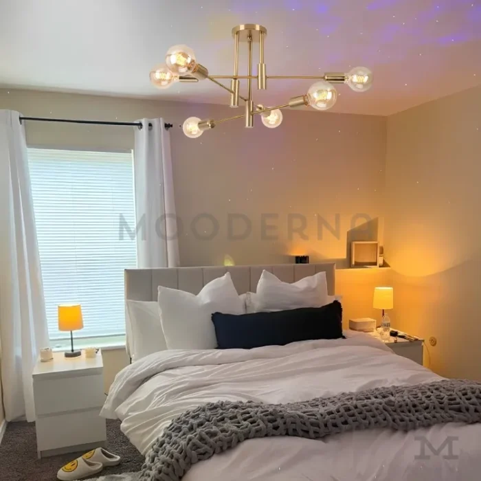 Lámpara Emma Gold en dormitorio con tonos tierra y cortinas claras.