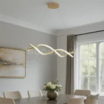 Luminaria dorada tipo onda instalada sobre comedor moderno de madera clara