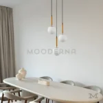 Luminaria Daysi Black and Gold instalada sobre comedor moderno. Su triple foco LED proyecta una luz cálida y elegante, destacando el contraste del negro satinado con el dorado. Ideal para ambientes con estilo contemporáneo y decoración minimalista.