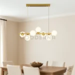 Luminaria dorada con esferas blancas instalada sobre comedor de 6 sillas color beige