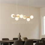 Comedor con pared clara y luminaria Hinata Gold central iluminando toda la mesa