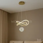 Luminaria Calix Gold instalada en sala elegante con decoración minimalista. Su diseño dorado brillante se integra perfectamente con tonos neutros, aportando lujo y luminosidad sin perder armonía visual.