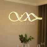 Luminaria Vittora Gold encendida en comedor contemporáneo. La luz LED de 60W baña el espacio con una iluminación uniforme y envolvente, resaltando el acabado metálico y las curvas del diseño.