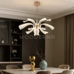 Luminaria Thea Gold encendida en comedor amplio. Los brazos curvados crean un efecto visual dinámico que complementa perfectamente la iluminación uniforme de 45W. Su acabado satinado resalta la elegancia del espacio.