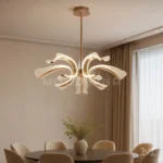 Luminaria Thea Gold instalada en comedor contemporáneo con tonos neutros. Su diseño artístico y luz LED ajustable en tres tonos crean una atmósfera cálida y lujosa que realza el diseño interior.