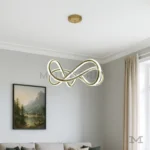 Luminaria Farella Gold encendida en sala elegante. Su luz LED de 60W ofrece una iluminación uniforme y envolvente, resaltando el brillo satinado del acabado dorado. Ideal para combinar con decoraciones neutras y modernas.