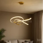 Luminaria Arisse Gold instalada en sala moderna. Su diseño ondulado en dorado refleja la luz de forma uniforme, creando un ambiente cálido y sofisticado. Ideal para destacar espacios contemporáneos con iluminación elegante.