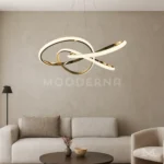 Luminaria Arisse Gold encendida en sala elegante. Proyecta una luz blanca suave y homogénea que realza la textura del ambiente. Su estructura curva añade movimiento visual y distinción decorativa.