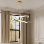 Luminaria Avéne Gold instalada en sala moderna. Su estructura circular con reflejos dorados distribuye una luz cálida y envolvente. Ideal para crear ambientes elegantes y acogedores en espacios de diseño contemporáneo.