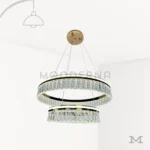 Luminaria Deline Gold sobre fondo blanco con diseño de doble aro suspendido en acabado dorado satinado. Fabricada en aluminio y acrílico con luz LED incorporada, combina estilo moderno y lujo contemporáneo ideal para destacar en catálogos de iluminación.