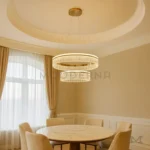 Luminaria Deline Gold instalada en comedor amplio con acabados neutros. Su luz LED ajustable realza la textura del entorno y crea una atmósfera acogedora. Ideal para espacios de alto diseño interior.