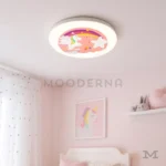 Luminaria Pink Cute instalada en habitación infantil decorada. Su luz LED cálida realza los colores pastel y crea una atmósfera mágica que invita al descanso y al juego. Ideal para techos bajos o medianos.