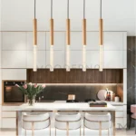 Abril Gold colocada sobre una isla de cocina, ofreciendo iluminación focal con un toque sofisticado gracias a su acabado dorado y diseño estilizado.