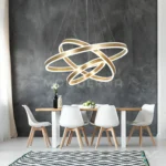 Vista de Helena Gold en sala amplia, destacando la composición escalonada de los anillos y su acabado dorado satinado.