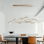 Vista de Nova Gold en comedor elegante, resaltando su forma fluida y la calidez de la luz LED.