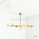 Adele Gold en fondo blanco, mostrando su diseño lineal con siete esferas de vidrio y estructura metálica en acabado dorado satinado.