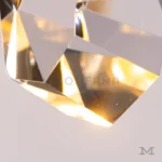 Detalle de lámpara colgante Candela Gold con cristal facetado e iluminación cálida