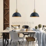 Dos lámparas colgantes negras y doradas Selavie Mix sobre mesa de comedor industrial